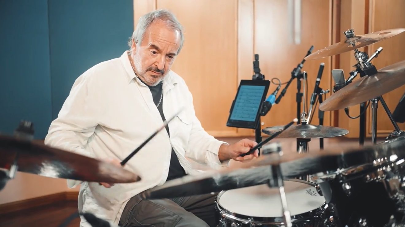 Luis Ceravolo at the drums in the studio, reading from a tablet, in the 500 Motivaciones video